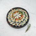 Overhead view of a 48 piece veggie maki platter with avocado rolls on a black catering tray