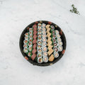 Overhead view of a 60 piece large maki platter on a black catering tray on a marble surface