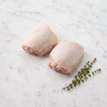 Two raw bone-in, skin-on chicken thighs with thyme sprigs on white marble