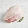 Raw bone-in, skin-on turkey breast without wings and a thyme sprig on white marble