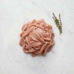 Mound of thinly sliced raw turkey for shawarma with thyme sprigs on white marble