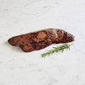 Kashered Beef Liver on a marble surface with a sprig of rosemary