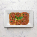 Overhead view of Beef Meatballs in Tomato Sauce on a white rectangular plate with basil