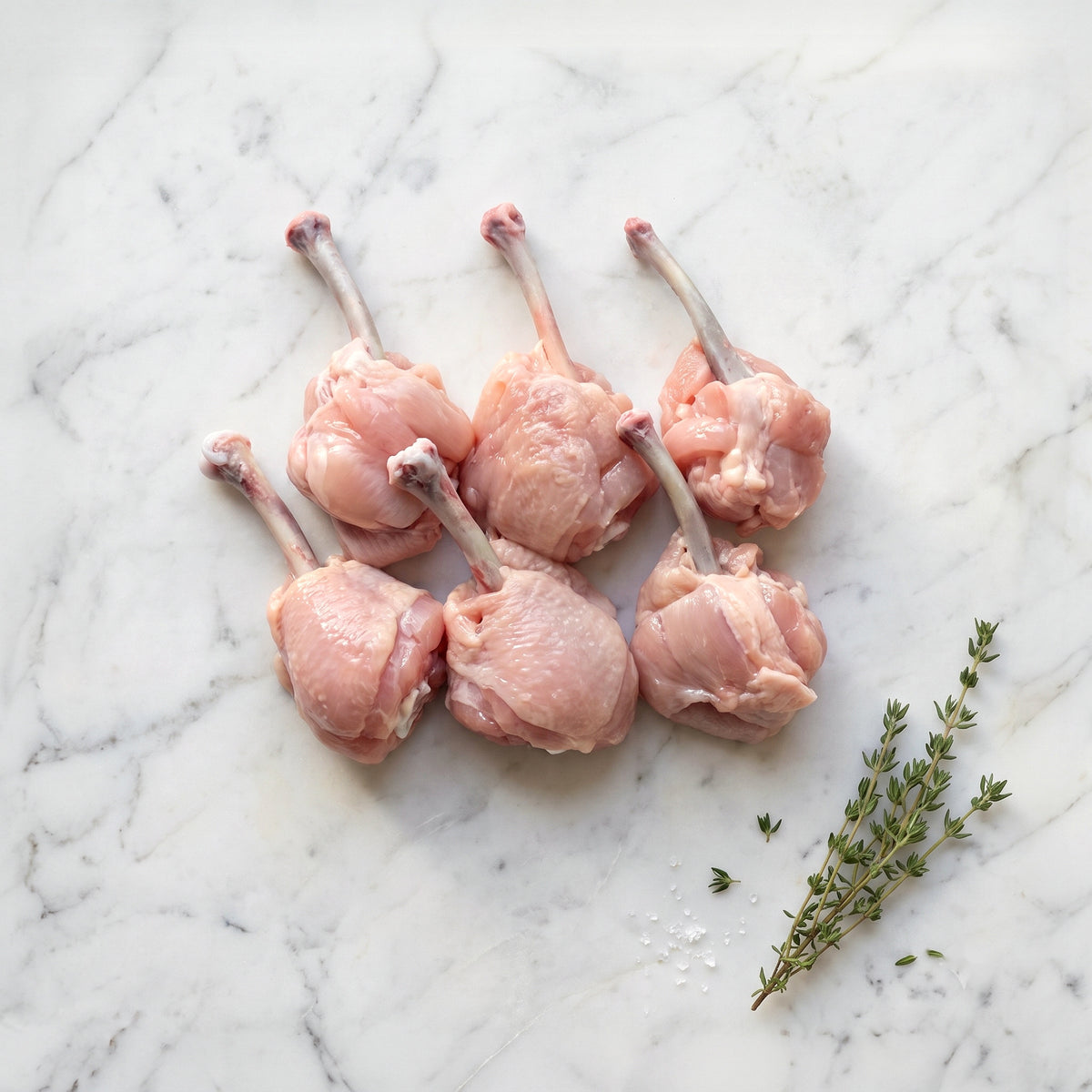 Raw chicken lollipops on a white marble surface