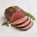 Cooked Roast Beef with a peppered crust, partly sliced to show a pink centre, on a marble surface