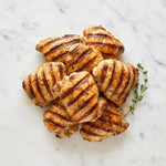 Overhead view of Grilled Boneless Chicken Legs with grill marks and thyme on a marble surface