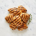 Overhead view of Grilled Boneless Chicken Legs with grill marks and thyme on a marble surface