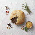 Overhead view of a Liver Knish broken open to show chopped liver filling, with mustard alongside