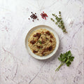Overhead view of a bowl of Orzo topped with caramelized onion and chopped parsley