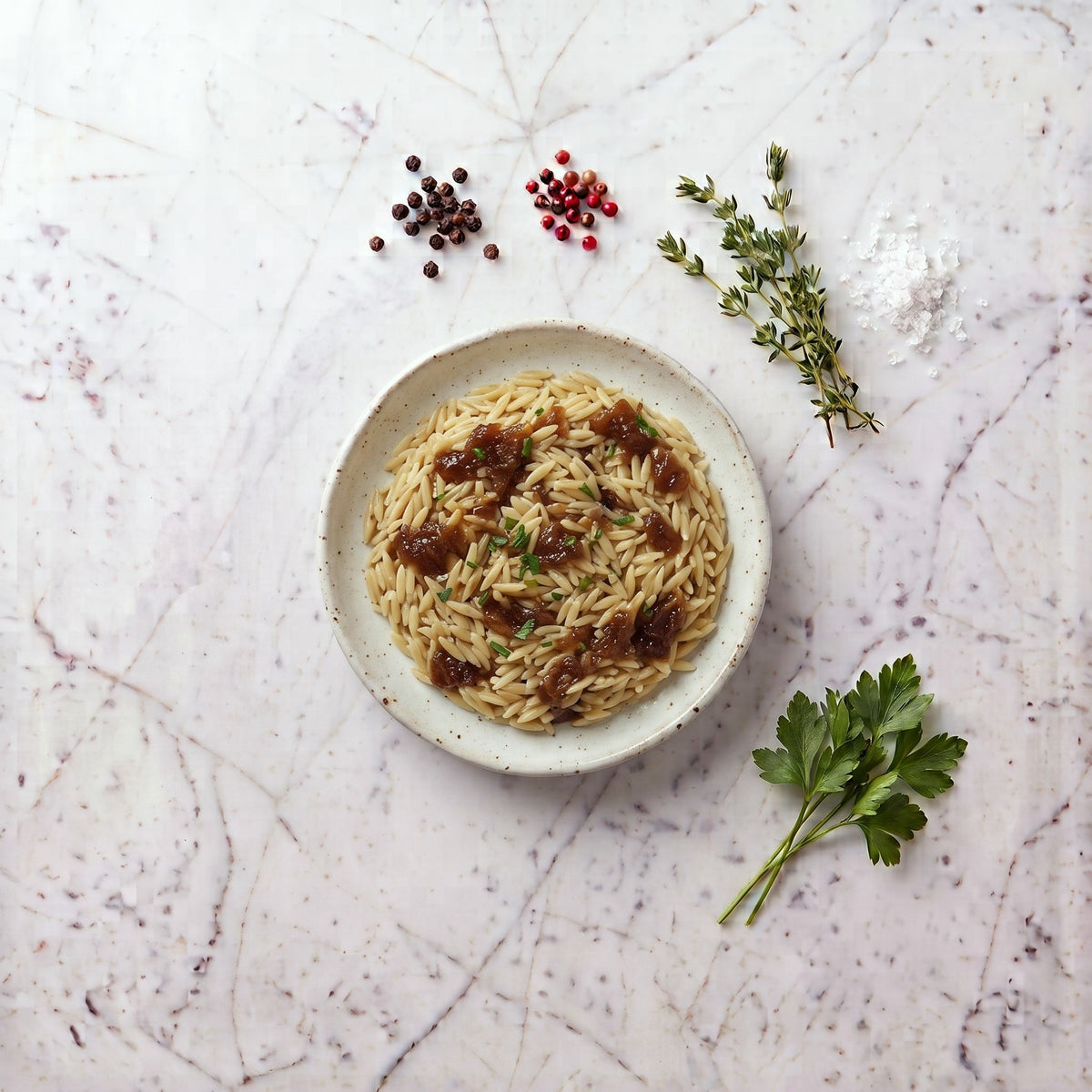 Overhead view of a bowl of Orzo topped with caramelized onion and chopped parsley
