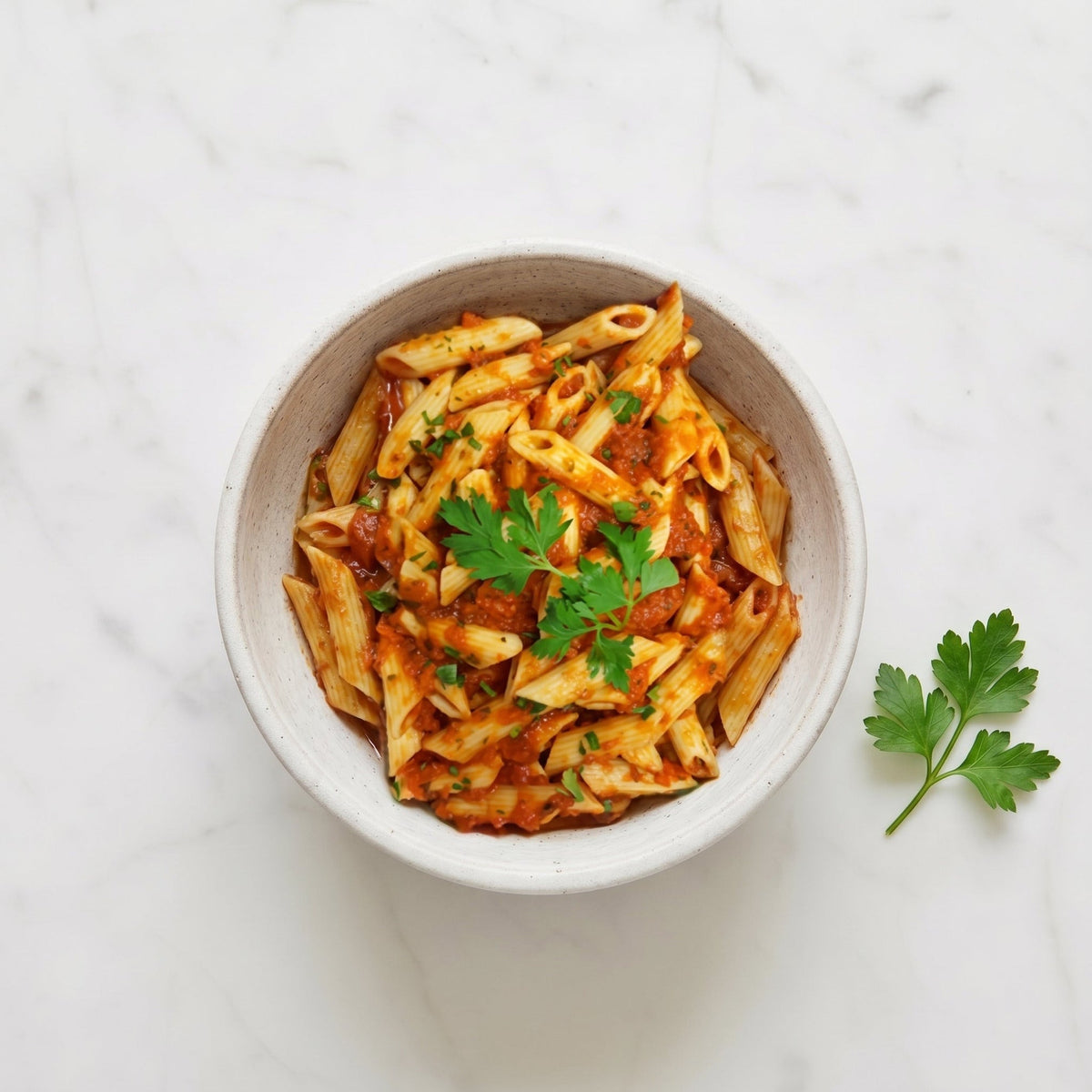 Overhead view of a bowl of Penne in Tomato Sauce garnished with parsley
