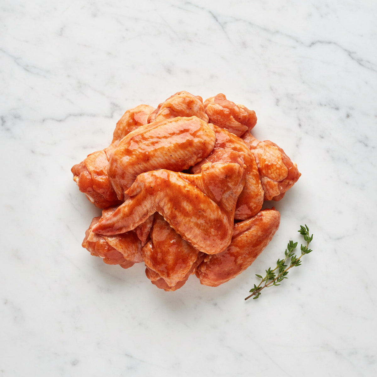 Pre-marinated chicken wings on a white marble surface