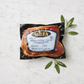 A packaged Shefa Smoked Turkey Thigh with sage leaves on a marble surface