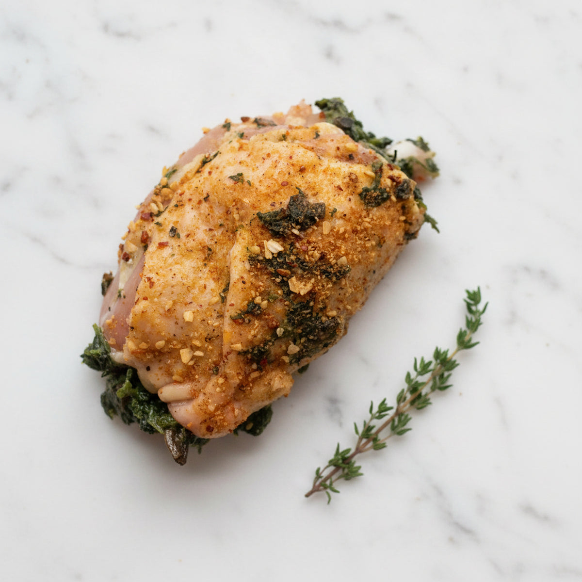 Boneless chicken thighs stuffed with mushroom and spinach on a white marble surface