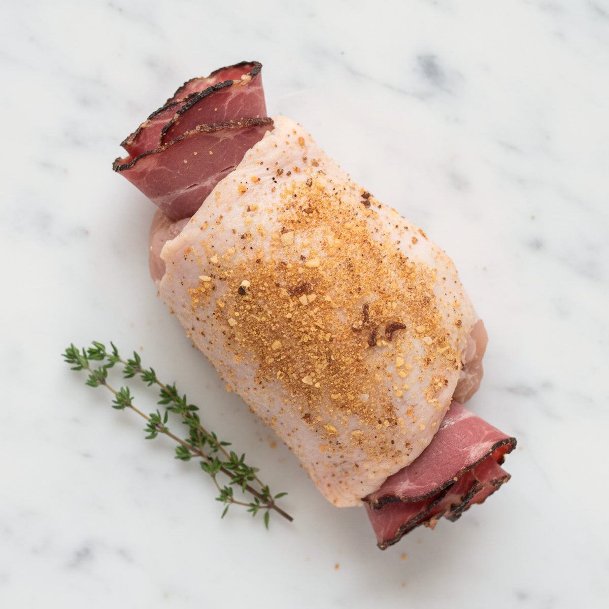 Boneless chicken thighs stuffed with pastrami on a white marble surface