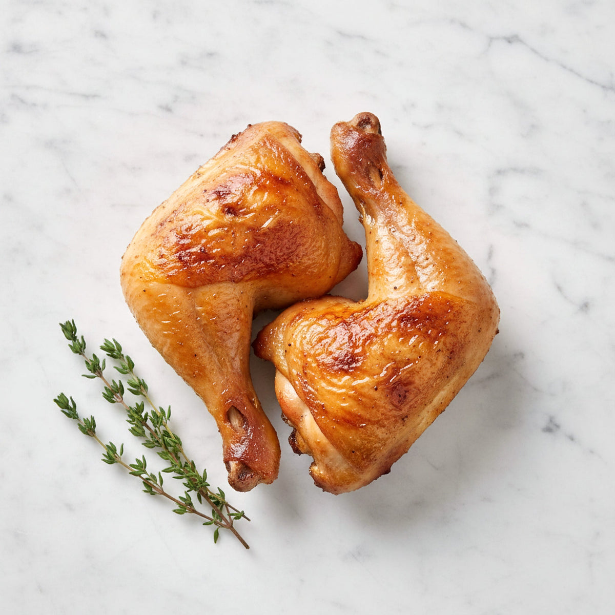 Overhead view of two TK BBQ or Roasted Chicken Legs with golden skin on a marble surface