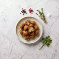 Overhead view of a plate of TK Breaded Cauliflower florets, golden fried, on a marble surface