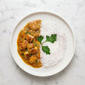 Overhead view of TK Chicken Curry with Rice, chicken in curry sauce beside white rice on a round plate