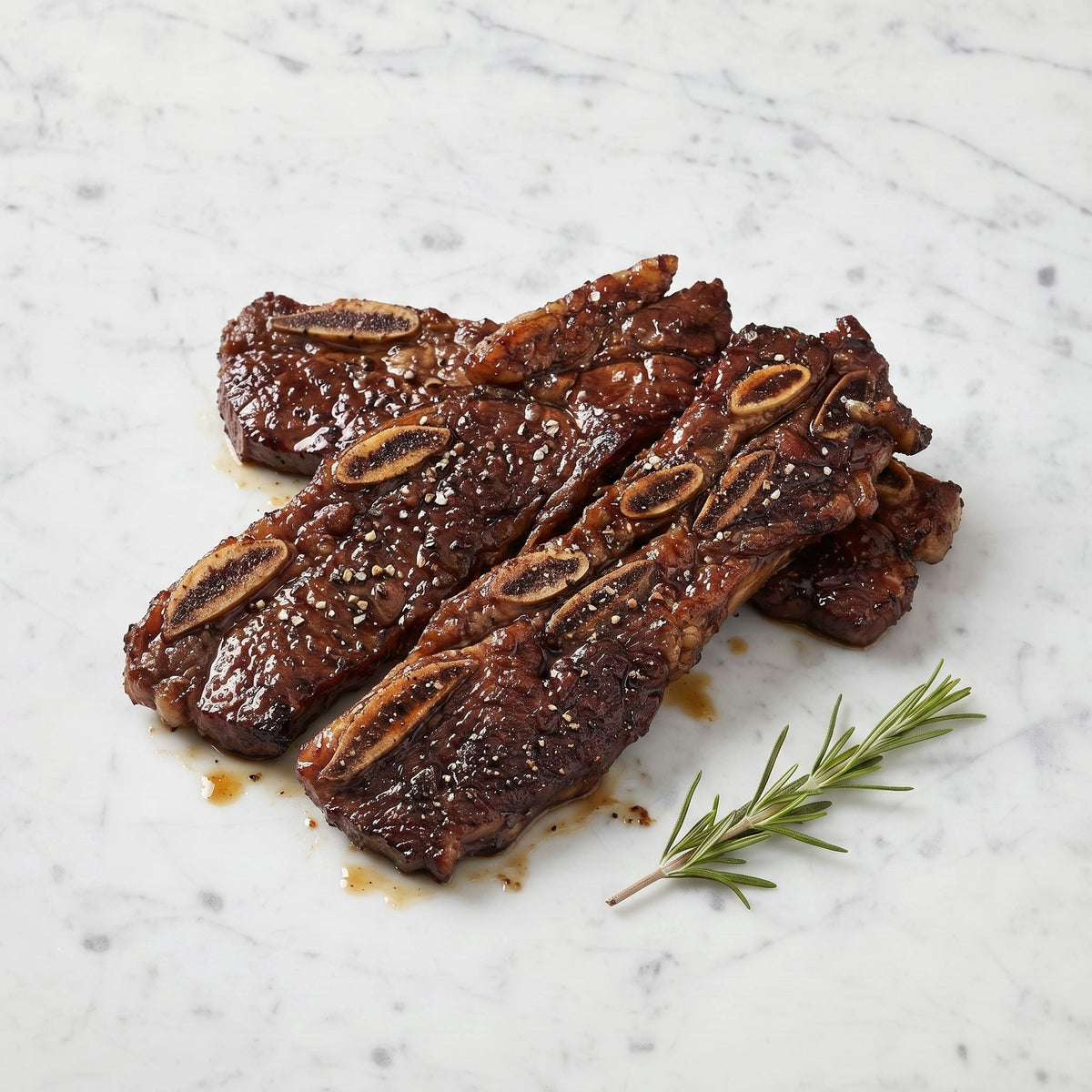 TK Grilled Miami Ribs, glazed flanken strips with cracked pepper and rosemary on a marble surface