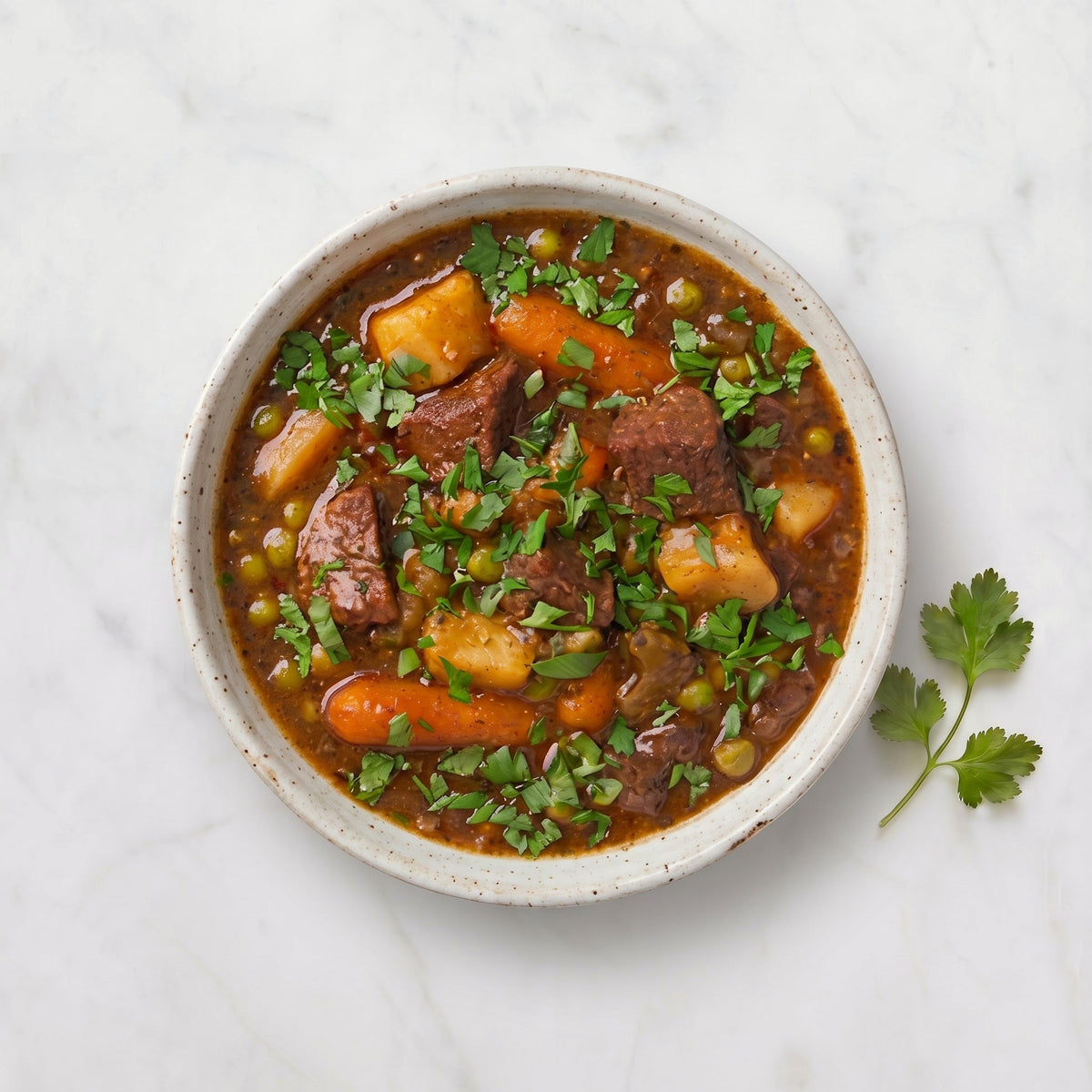 Overhead view of a bowl of TK Hearty Beef Stew with carrot, potato, peas and parsley