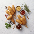 Overhead view of TK Pre-Cooked All Beef Corn Dogs with mustard, ketchup and relish on marble