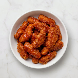 Overhead view of a bowl of TK Pre-Cooked Chicken Poppers in a glossy sauce