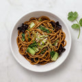 Overhead view of a bowl of TK Shanghai Noodles with bok choy, scallion and black fungus