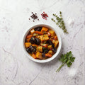 Overhead view of a bowl of TK Tzimis with carrots, sweet potato, prunes and raisins