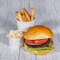 Beef burger with tomato, red onion and lettuce, with a cup of fries and coleslaw on a wooden table