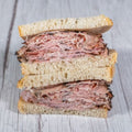 Montreal smoked meat sandwich on rye, cut and stacked, on a wooden table