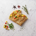 Overhead view of two folded Vegetable Crepes filled with mixed vegetables on a marble surface