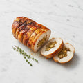 Whole Stuffed Boneless Chicken roast, partly sliced to show the stuffing, with thyme on a marble surface